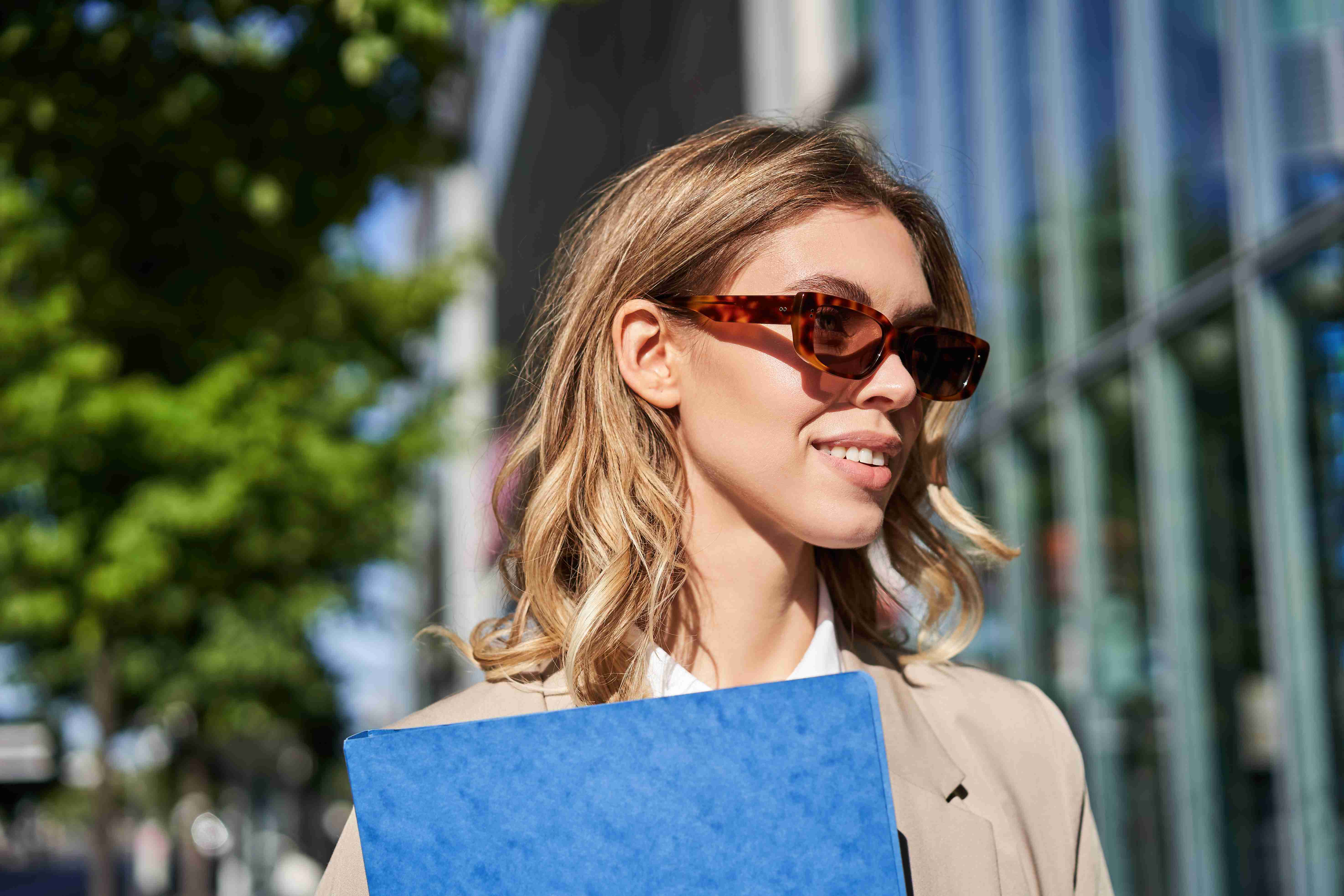 close-up-portrait-smiling-young-woman-sunglasses-corporate-suit-holding-folder-with-work-doc (1)_11zon.jpg